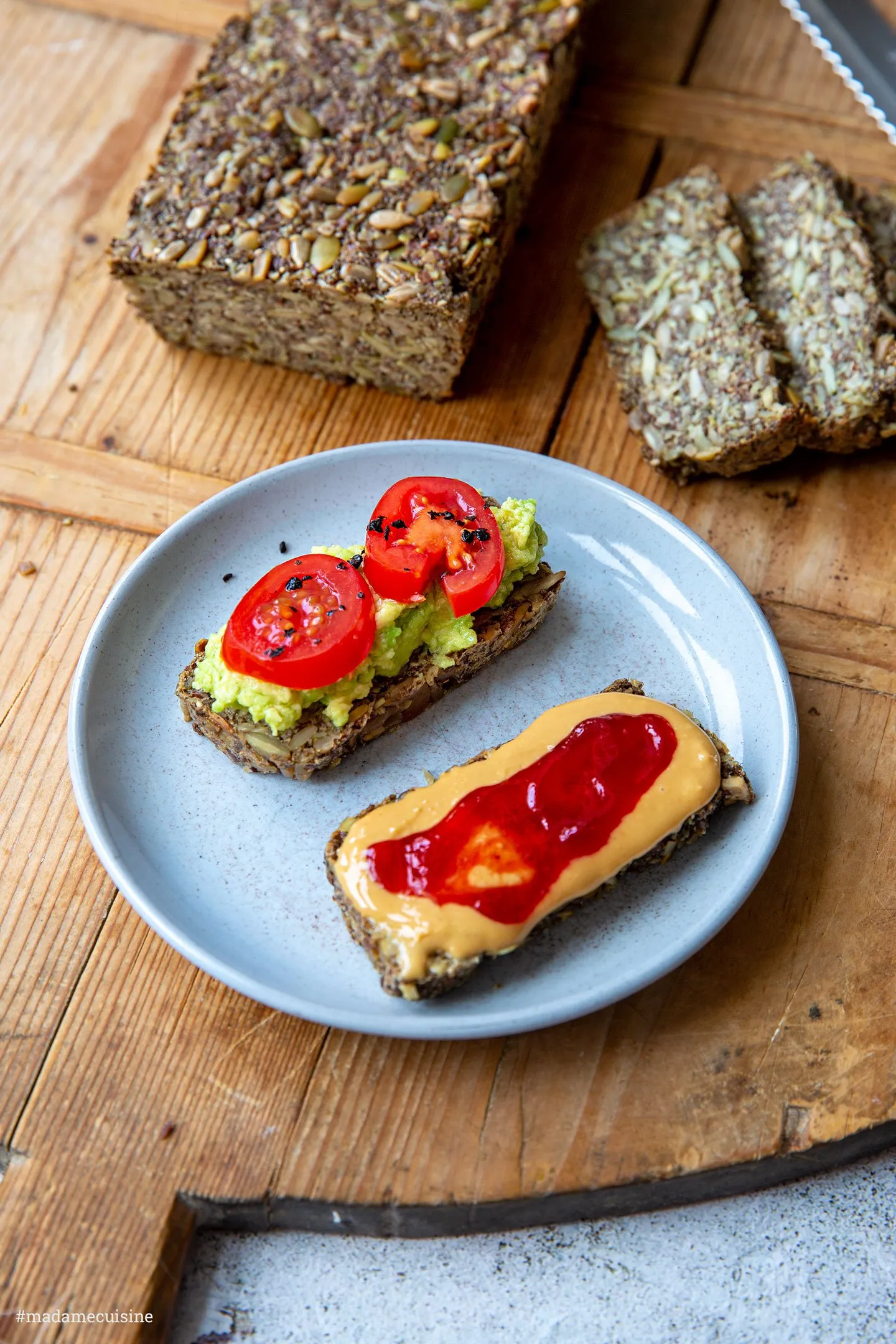 Mehrere Scheiben des glutenfreien Körnerbrots liegen auf einem Holzbrett, umgeben von Sonnenblumen- und Kürbiskernen