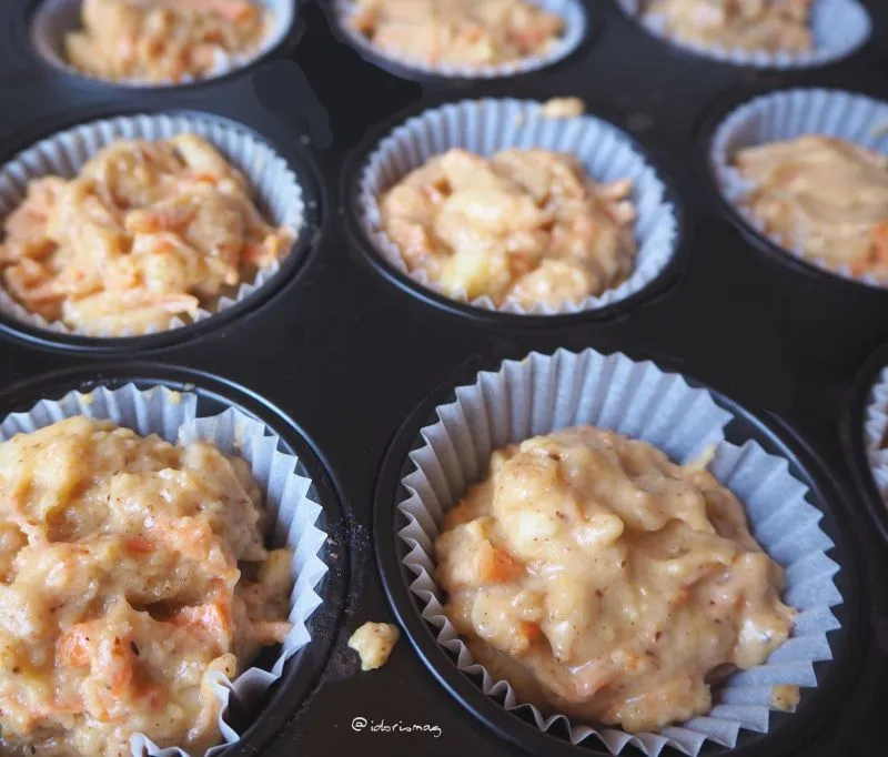 Muffinformen mit Papierförmchen, die mit dem vorbereiteten Teig befüllt werden, bereit zum Backen