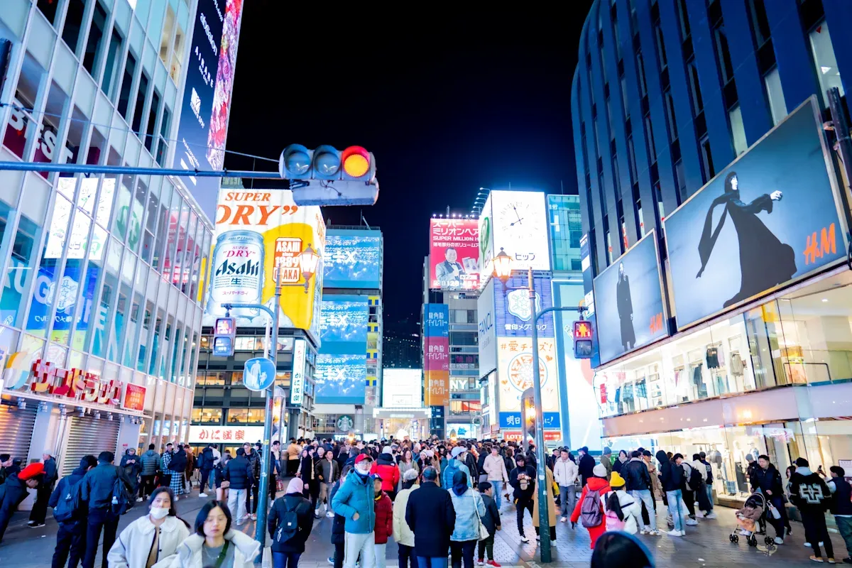 Nachts belebte Straßen in Osaka mit Touristen