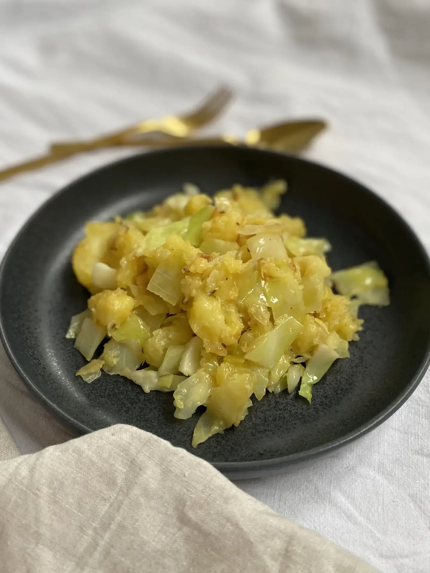Nahaufnahme der cremigen vegetarischen Kartoffel-Kraut-Pfanne mit frischen Kräutern, angerichtet in einer Pfanne