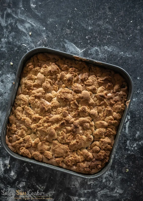 Nahaufnahme der Zutaten für den Kuchen: Trockenfrüchte, Nüsse, Marmelade und Teigzutaten bereit zur Verarbeitung.