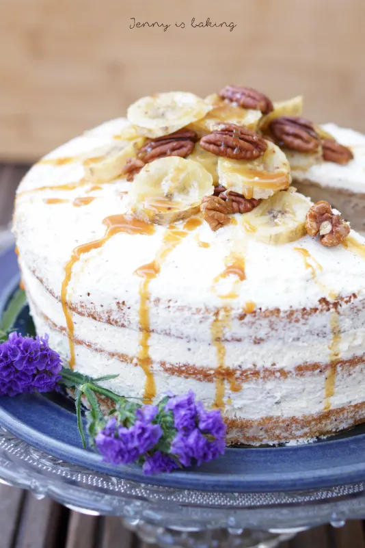 Nahaufnahme einer fertig dekorierten Bananen-Buttercremetorte mit Nüssen und Karamellsoße