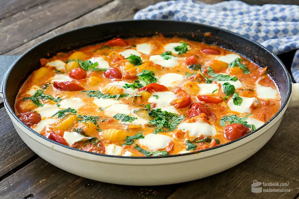 Nahaufnahme einer Pfanne mit Gnocchi, Tomaten und Büffelmozzarella vor dem Gratinieren