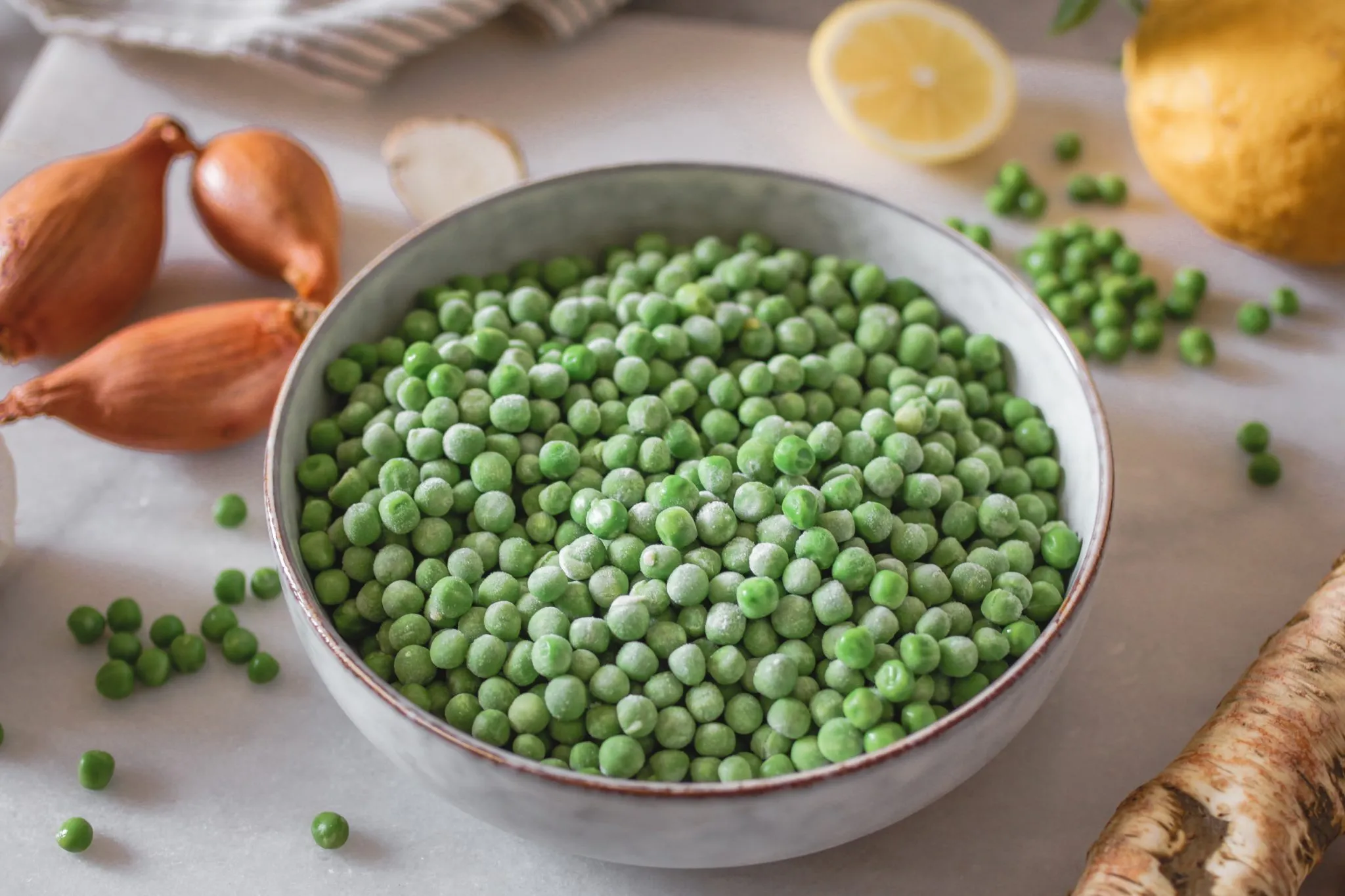 Nahaufnahme einer Portion Erbsen-Kokossuppe, garniert mit frischer Kresse und Erbsen