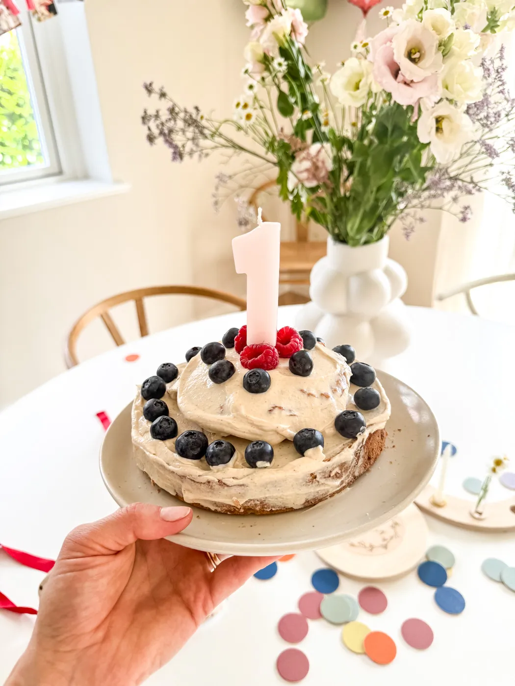 Nahaufnahme eines geschichteten Babykuchens, dekoriert mit Beeren und einer zarten Frischkäsecreme