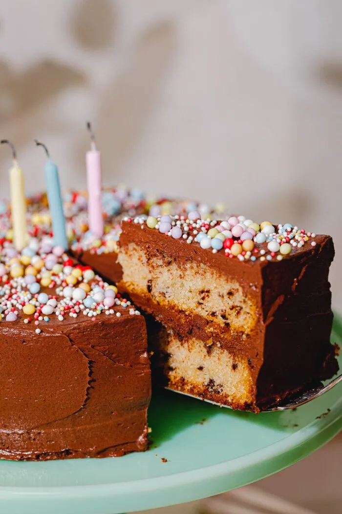 Nahaufnahme eines Stücks veganen Geburtstagskuchens mit Schoko-Frosting