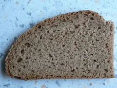 Nahaufnahme eines Weizenvollkornbrots, dessen Schnittfläche die dichte Textur und die sichtbaren Körner zeigt