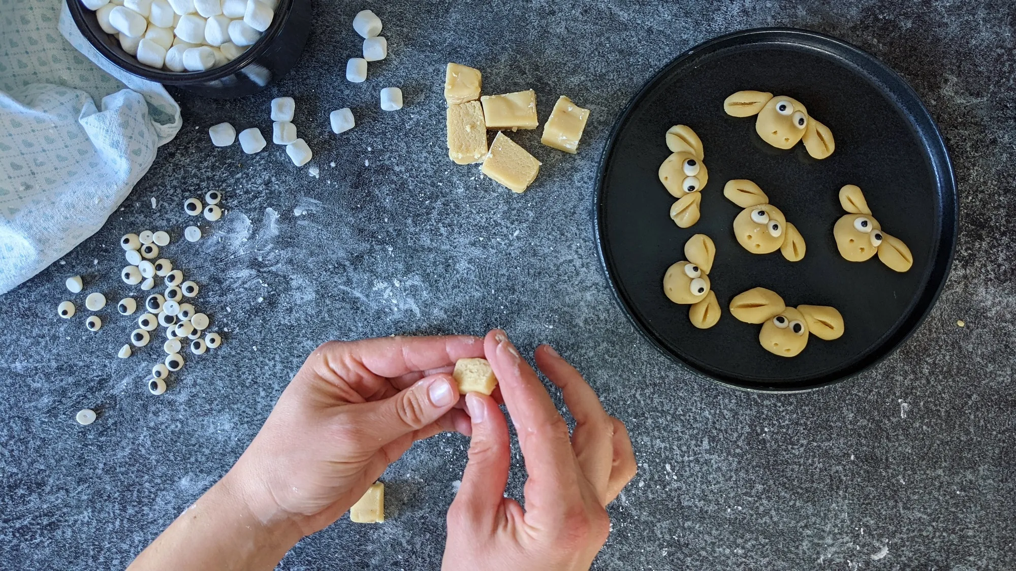Nahaufnahme von Marzipan-Schafköpfen mit Zuckeraugen auf einem Holzbrett