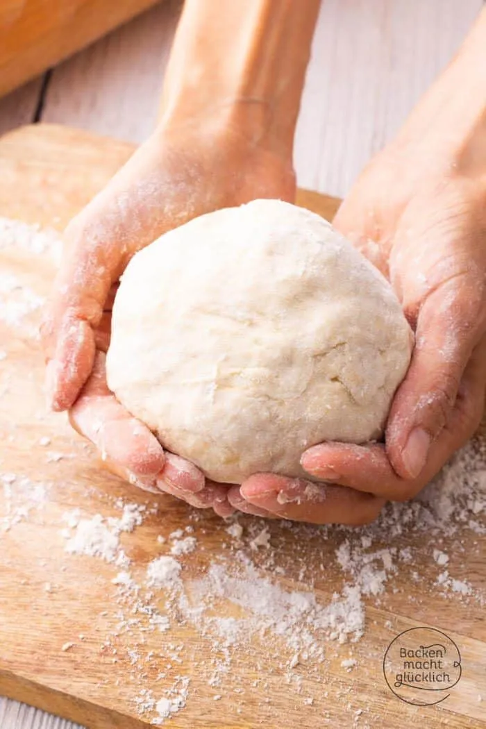 Nahaufnahme von selbstgemachtem Flammkuchenteig auf einer bemehlten Arbeitsfläche