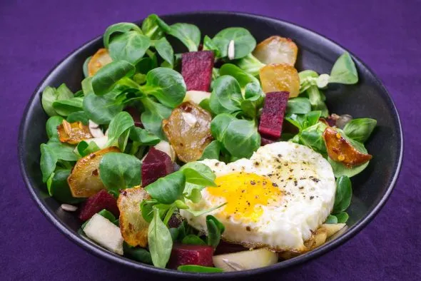 Nahaufnahme von Topinambur-Scheiben, die in einer Pfanne goldbraun gebraten werden, um eine knusprige Textur zu erzielen