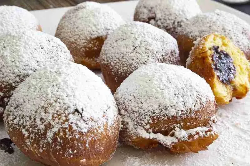 Nahaufnahme von zwei Berliner Pfannkuchen, reichlich mit Puderzucker bestreut