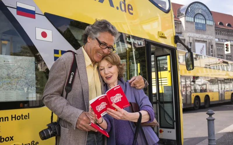 Paar vor einem Sightseeing-Bus in Berlin bei sonnigem Wetter