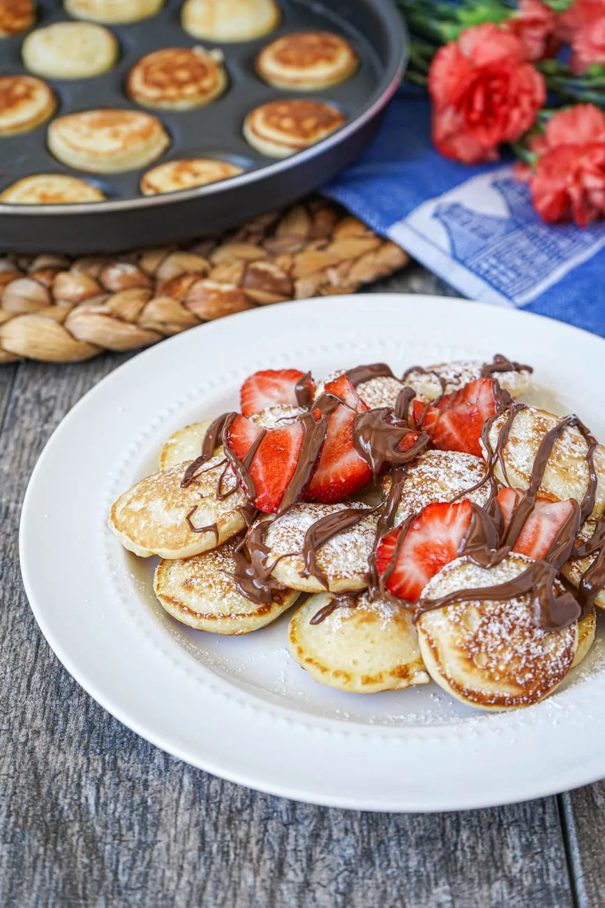 Poffertjes (Holländische Mini-Pfannkuchen) garniert mit frischen Erdbeeren und Nutella.