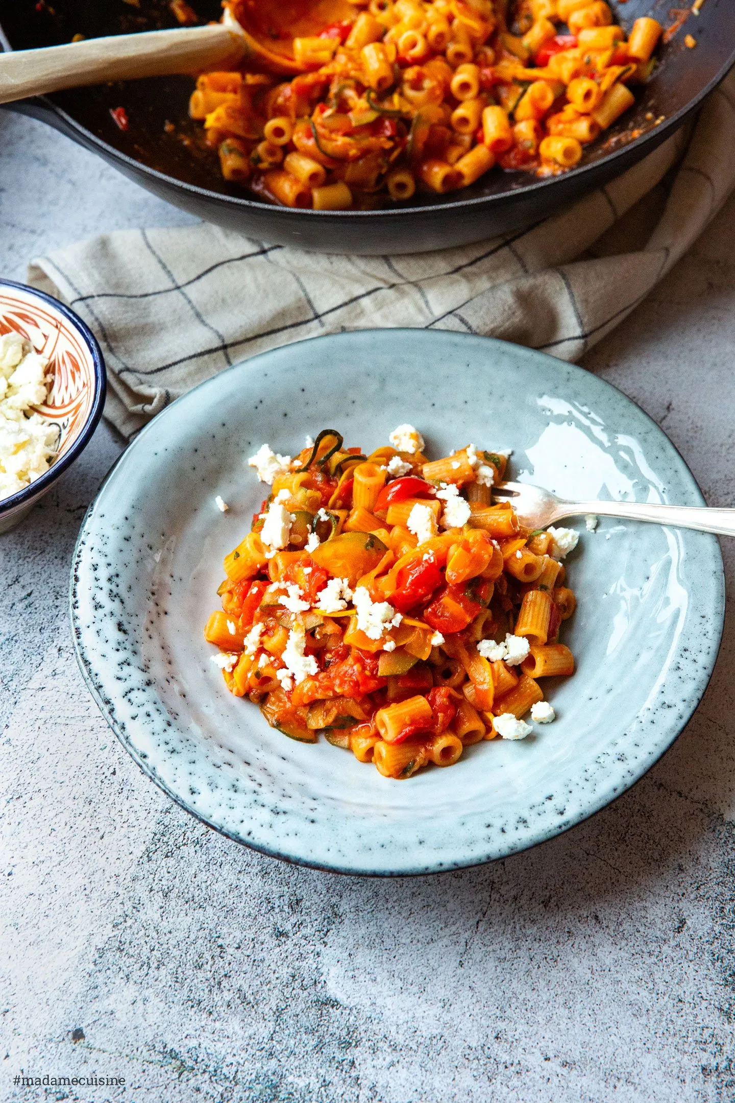 Portionen von frischer Gemüse-Pasta mit Feta und Kräutern auf zwei Tellern