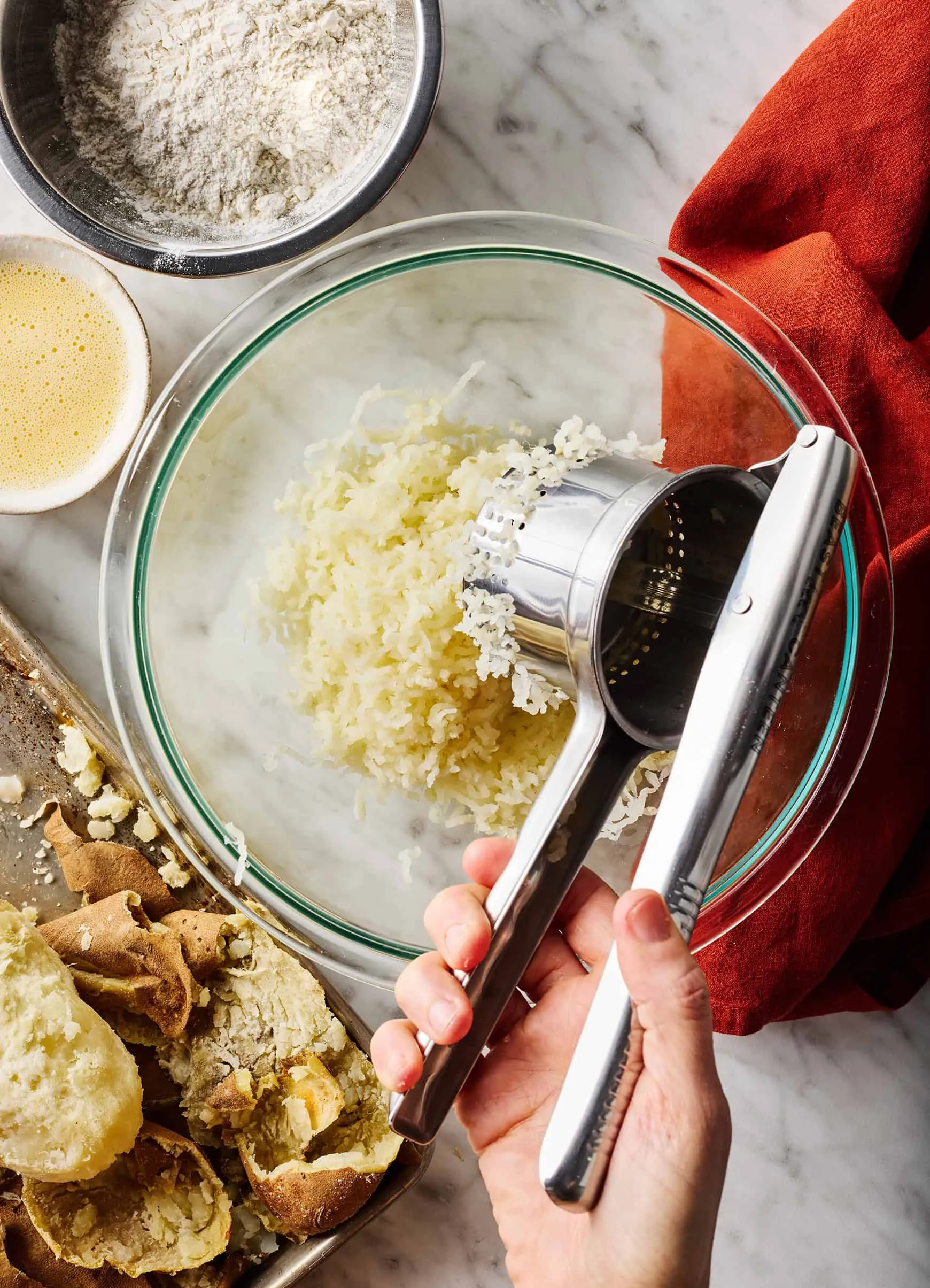 Pürierte Kartoffeln werden durch eine Kartoffelpresse gedrückt für den Gnocchi-Teig