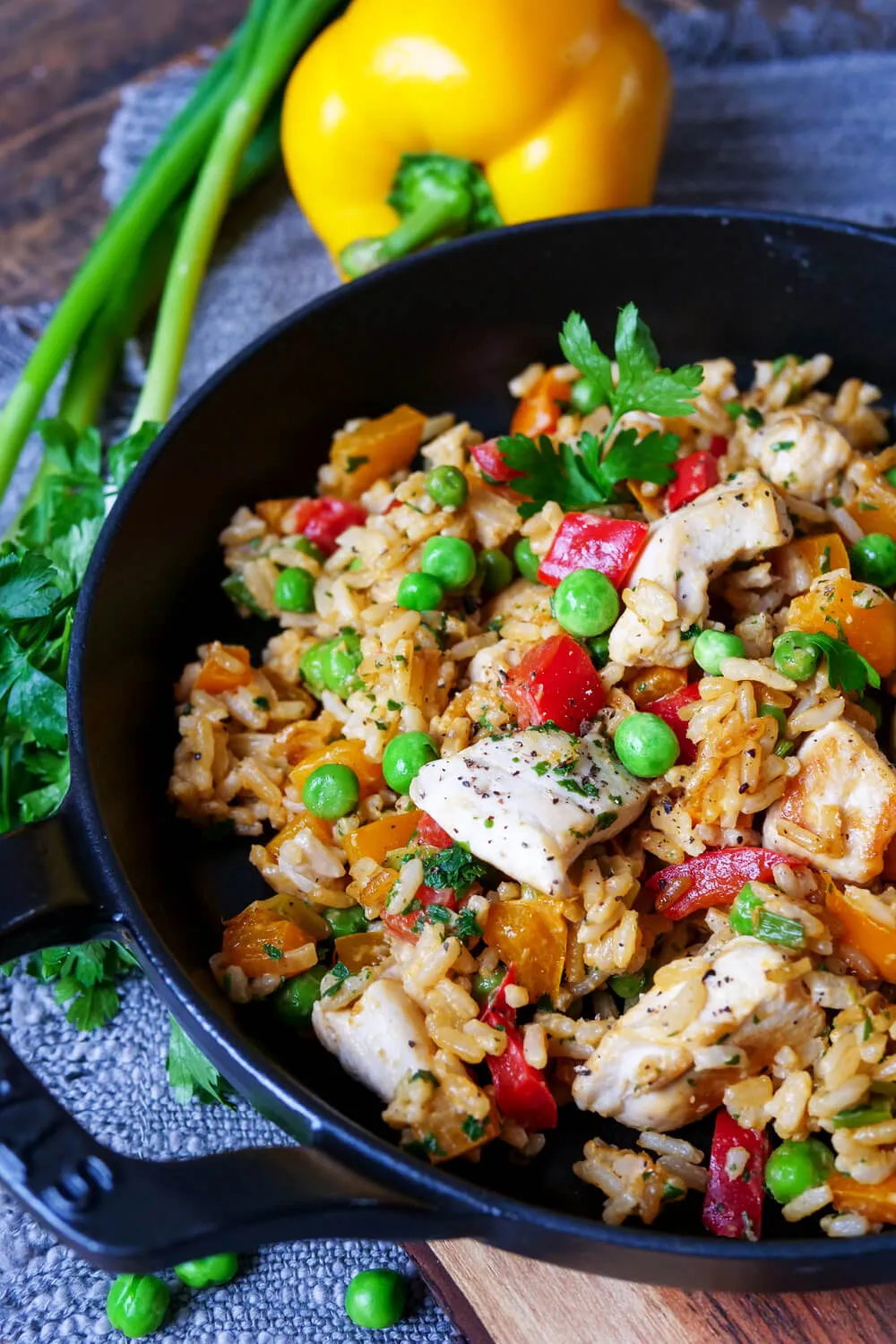 Reispfanne mit Hähnchen, Paprika und Erbsen in einer gusseisernen Pfanne