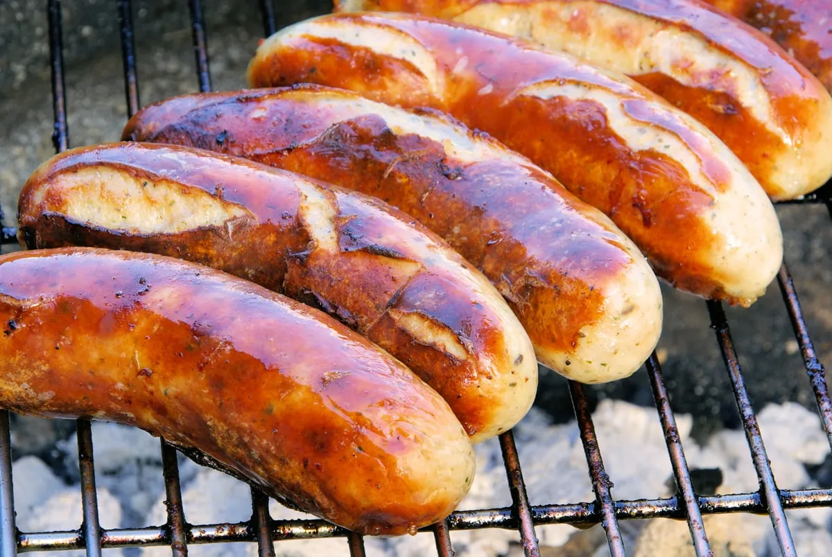 Saftige deutsche Bratwürste brutzeln auf dem Grill, bereit für die Currywurst-Zubereitung
