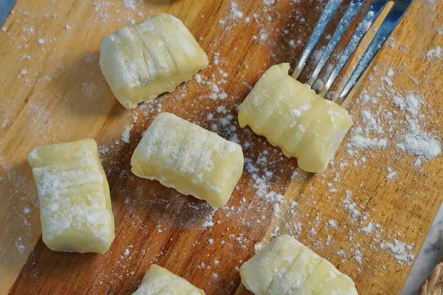 Selbst gemachte Gnocchi in einer Schüssel, bereit zum Kochen, mit rustikalem Holzuntergrund