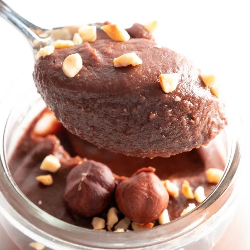 Selbstgemachte Keto Nuss-Nougat Schoko-Creme in einem Glas mit Haselnüssen