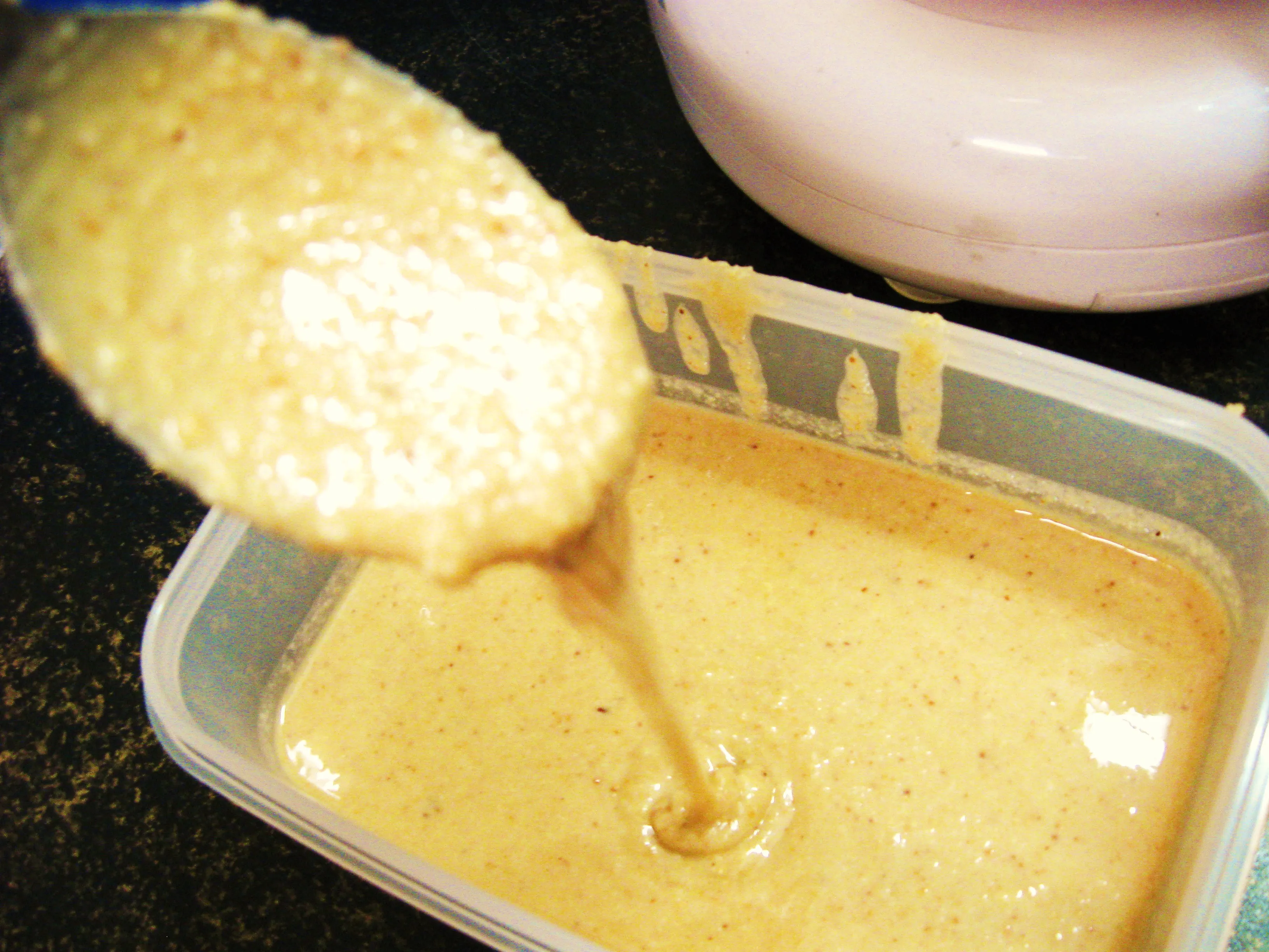 Selbstgemachtes Mandelmus in einem kleinen Glasgefäß mit Holzdeckel