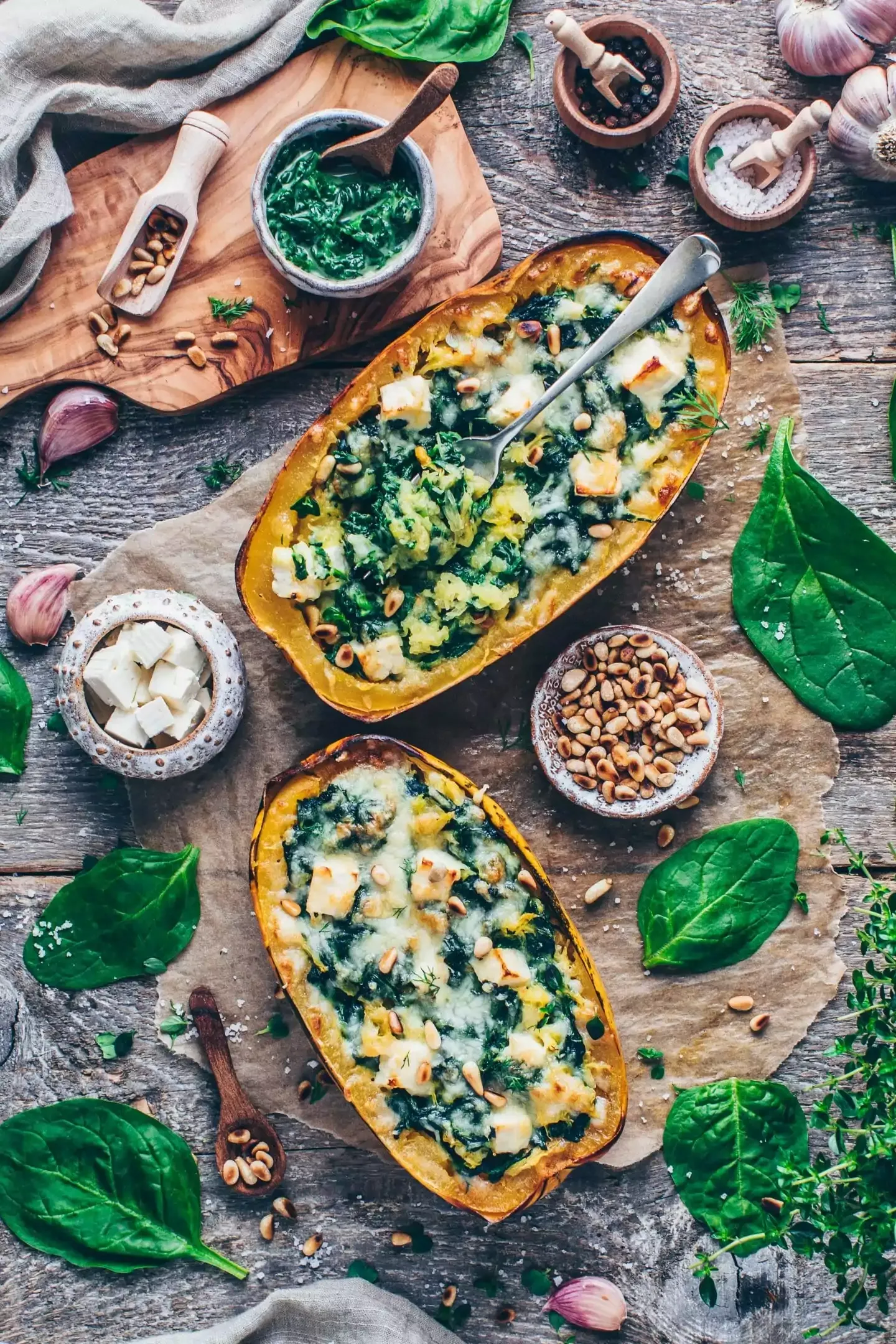Servierfertige Spaghetti-Kürbis-Boote mit Spinat, veganem Feta und Pinienkernen