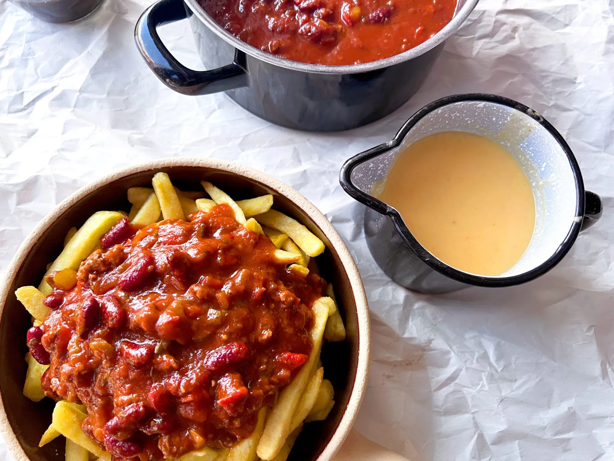Servierte Chili Cheese Fries mit Sauerrahm und frischen Kräutern