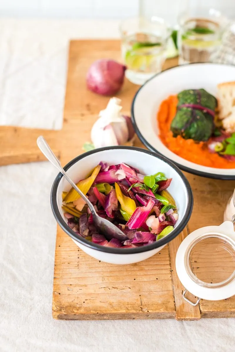 Servierte vegetarische Mangold-Roulade auf einem Teller mit Kräutern als Garnitur
