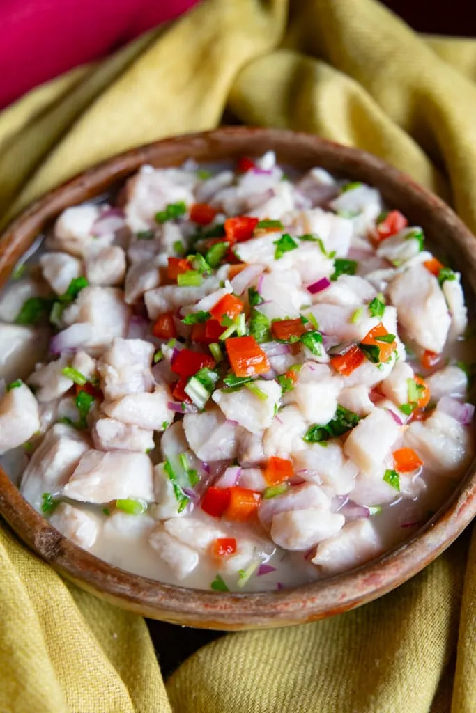 Serviertes Fisch-Ceviche in einer braunen Schüssel auf einem hellgelben Tuch, fertig zum Genießen