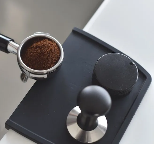 Siebträgermaschine mit Mahlwerk, die frisches Kaffeepulver in den Siebträger füllt.