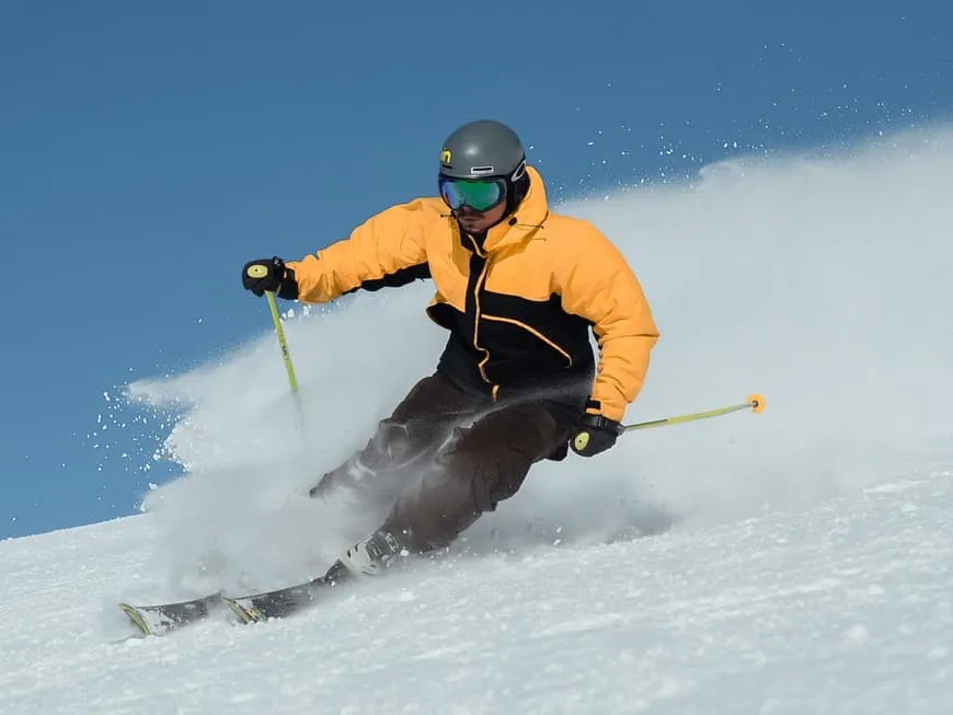 Skifahrer in voller Fahrt auf einer verschneiten Piste bei Sonnenschein