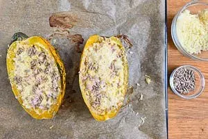 Spaghettikürbis mit Käse und Sonnenblumenkernen bestreuen und im Backofen fertig backen