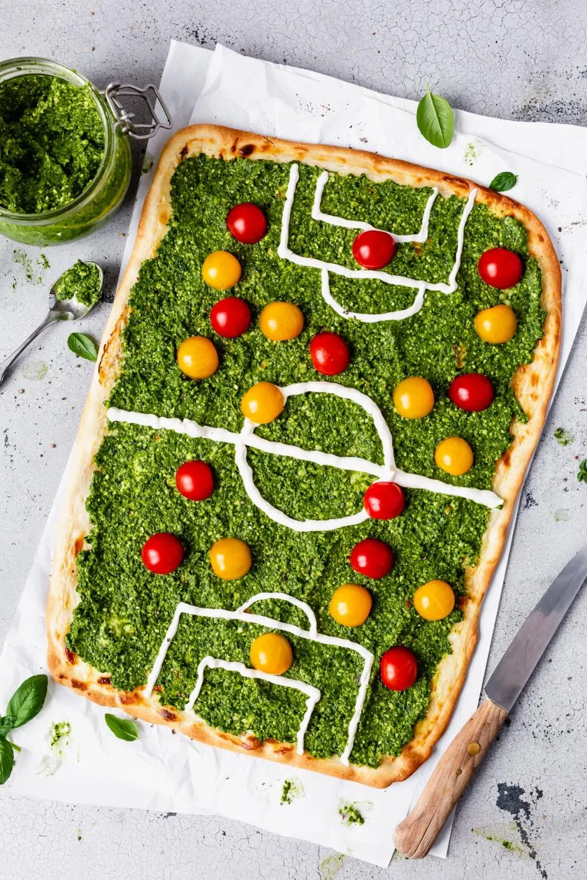 Spinat-Pesto und bunte Tomaten als Fußballfeld