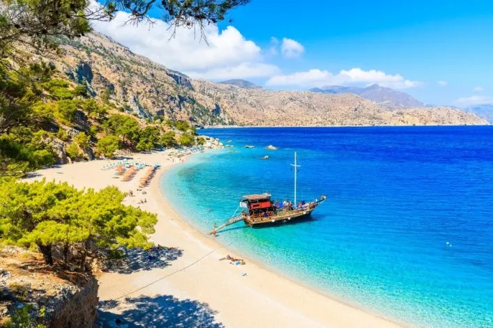 Steile Küstenlinie mit Pinien, türkisfarbenes Meer und Sandstrand auf der Insel Karpathos