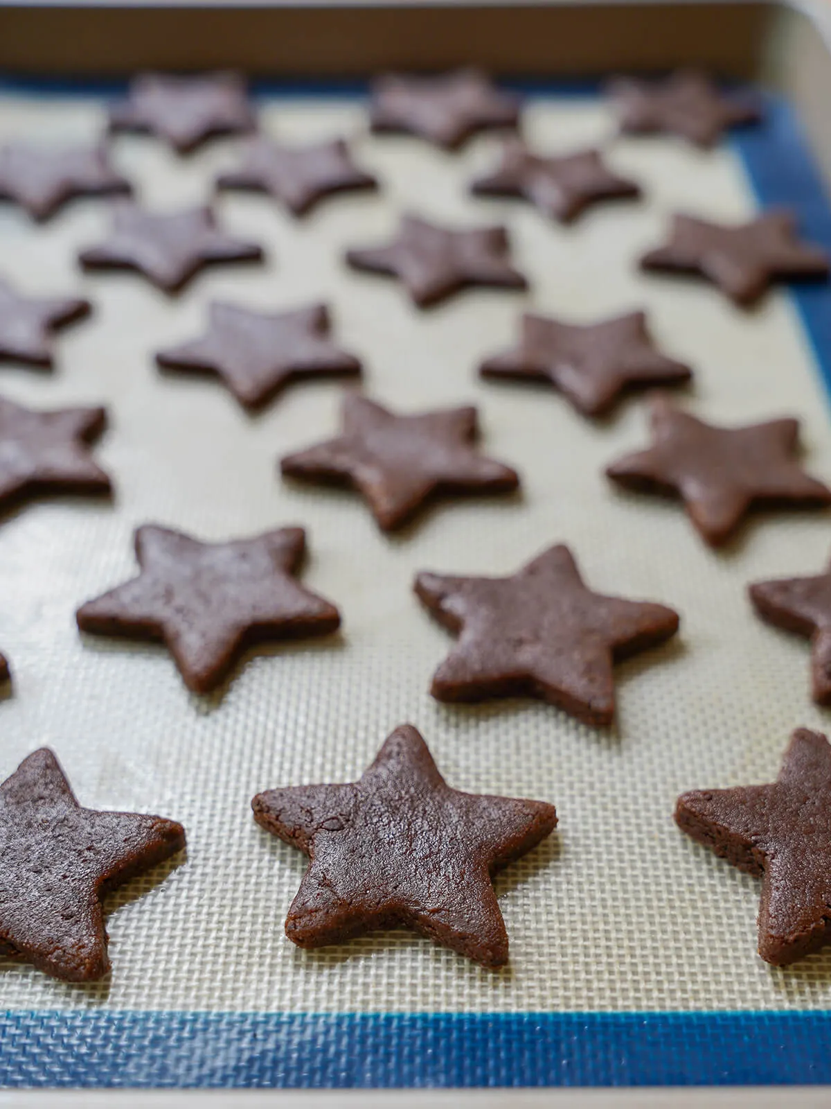 Sterne-förmige Kekse auf einem Backblech vor dem Backen, die an der Luft trocknen.