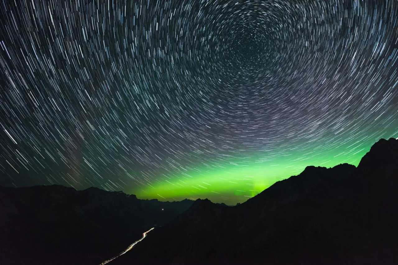 Sternenspur mit Aurora über LKW-Lichtspur in Kananaskis, Alberta