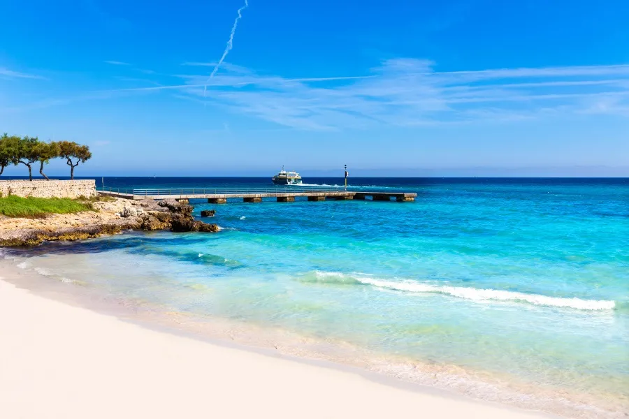 Strahlender Sandstrand in Cala Millor, Mallorca, mit türkisblauem Wasser und sanften Wellen