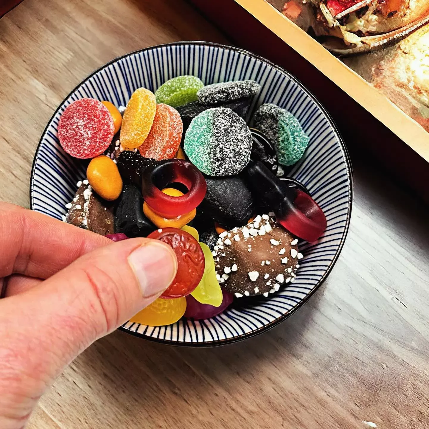 Süße Lakritz-Mischung mit verschiedenen Formen und Farben in einem Holzbehälter, bereit zum Probieren