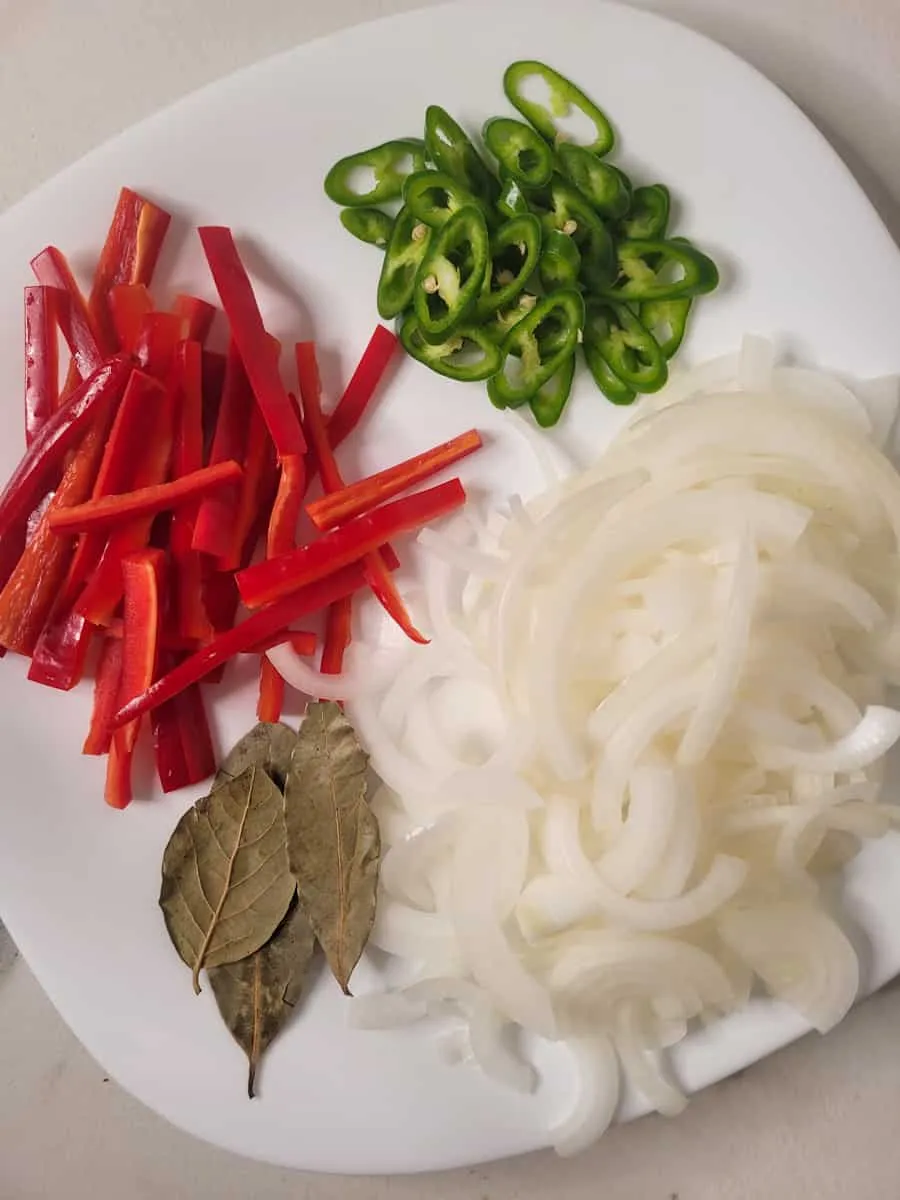 Teller mit geschnittenen Paprika, Zwiebeln und Lorbeerblättern