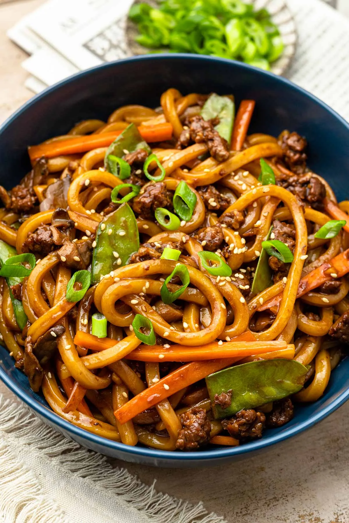Teriyaki Udon Nudeln in einer Schüssel, garniert mit Sesam und Frühlingszwiebeln