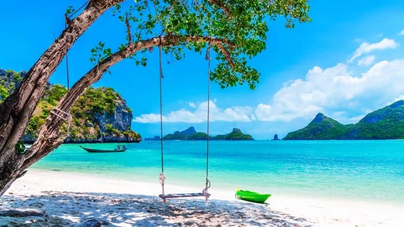 Traditionelles Longtail-Boot im klaren Wasser einer thailändischen Bucht mit Kalksteinfelsen