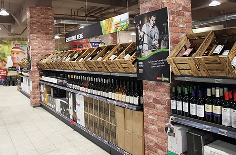 Übersichtlicher Gang im Markgrafen Getränkemarkt Naumburg mit modernen Regalen und Weinflaschen in Holzkisten