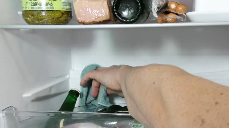 Verbliebenes Kondenswasser im Kühlschrank wird mit einem Tuch entfernt.