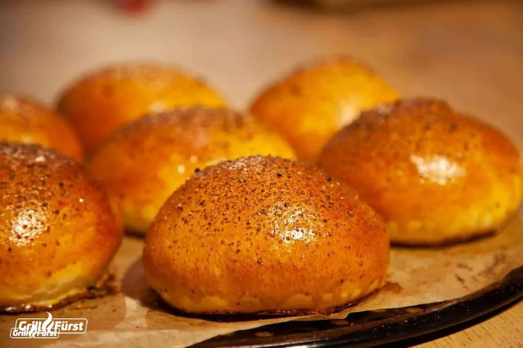Vier goldbraune Burgerbrötchen frisch aus dem Ofen, bereit zum Belegen