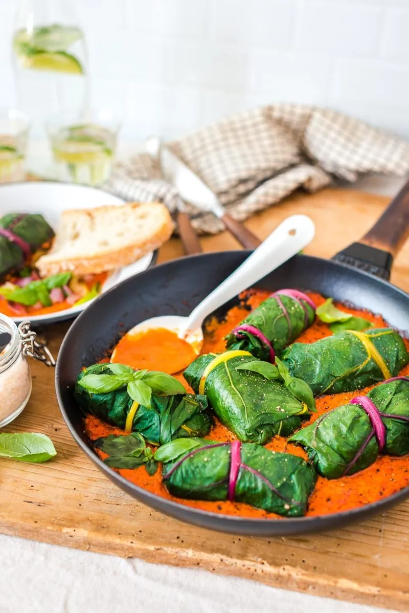 Vier vegetarische Mangold-Rouladen in cremiger Paprikasauce in einer rustikalen Auflaufform