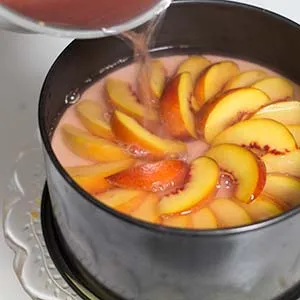 Vorsichtiges Übergießen der Pfirsiche mit dem selbstgemachten, leicht rosafarbenen Gelee