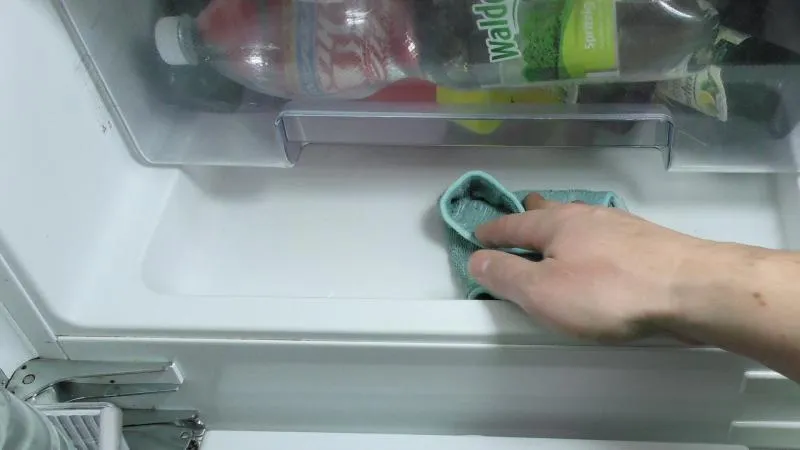 Wasser im Kühlschrank mit einem Lappen entfernen.