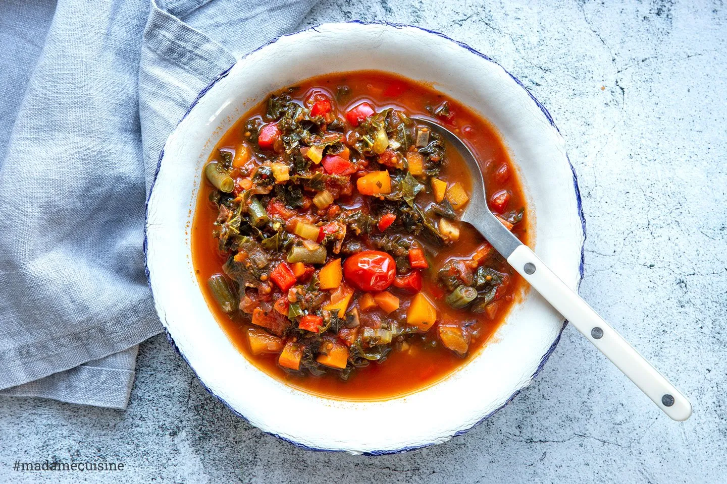 Winterliches Ratatouille in einer rustikalen Schale auf einem Holztisch, dekoriert mit frischen Kräutern