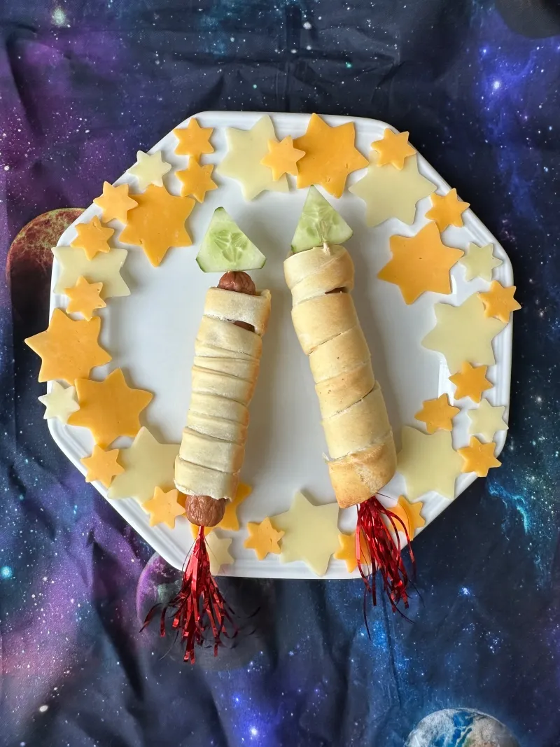 Würstchen, umwickelt mit Pizzateig und aufgespießt, die wie kleine Raketen aussehen – ein deftiger Snack für die Party.