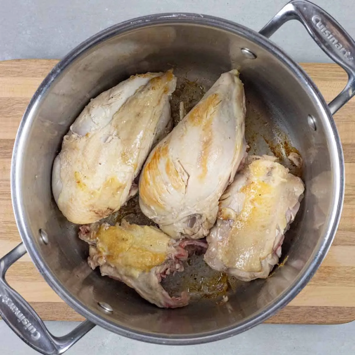 Zerlegte Hähnchenteile braten in einem großen Topf an.