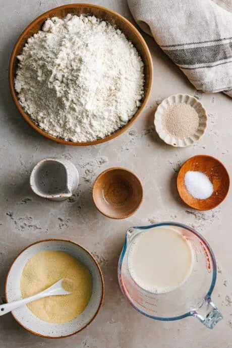 Zutaten für böhmische Knödel auf einem Holztisch: Mehl, Grieß, Hefe, Öl, Salz und Hafermilch